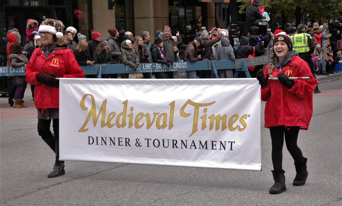 2 volunteers carrying a Medieval Times banner in the Chicago Thanksgiving Parade