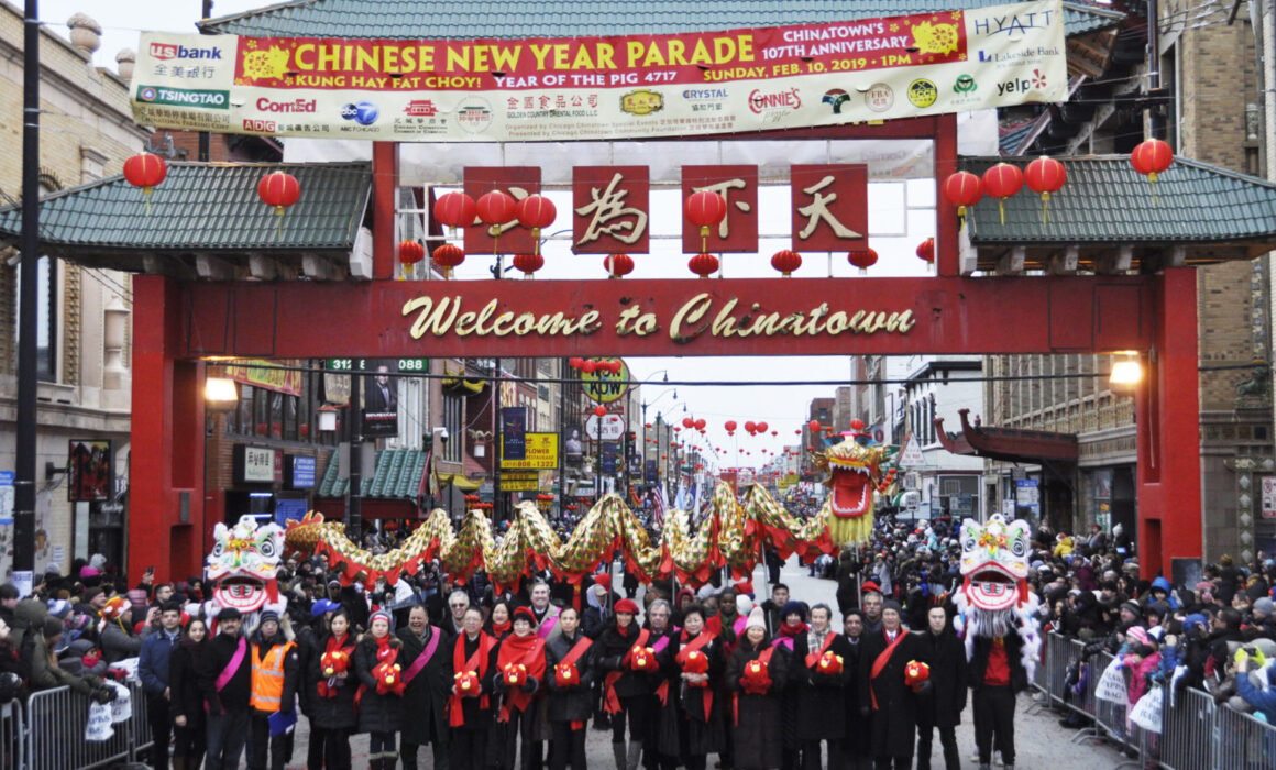 Parade participants posting in front of the Gateway in Chinatown (Chicago), holding a ceremonial dragon during the Chinese New Year Parade