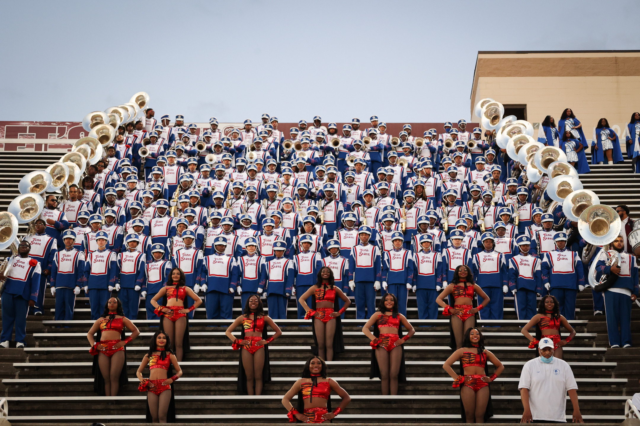The Tennessee State University Marching Band sitting in the stands of their stadium. The color guard is in the foreground, with the band in the back.