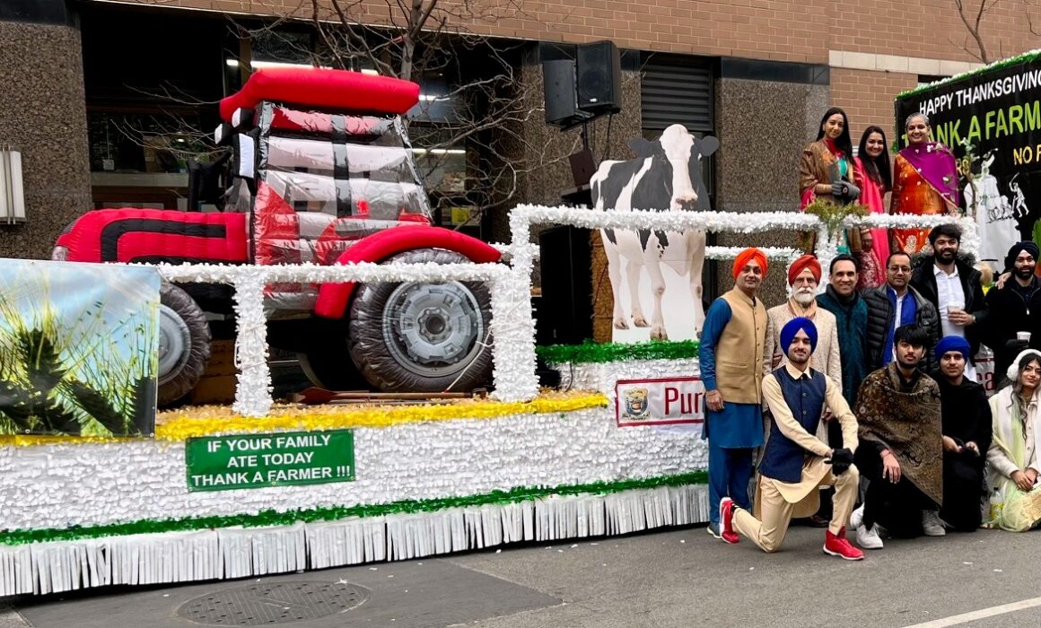 The Punjabi Cultural Society of Chicago's "Thank a Farmer" float, featuring an inflatable tractor. Members of the society are wearing traditional outfits while standing and posing for the camera in front of the float.